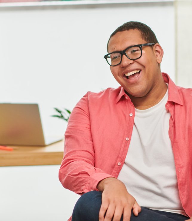 Close up portrait of happy, confident young man with autism and vitiligo in office laughing
